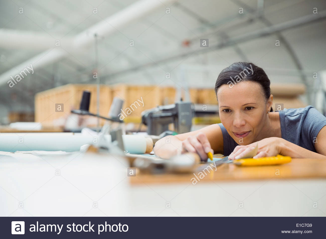 Worker with ruler in textile manufacturing plant Stock Photo