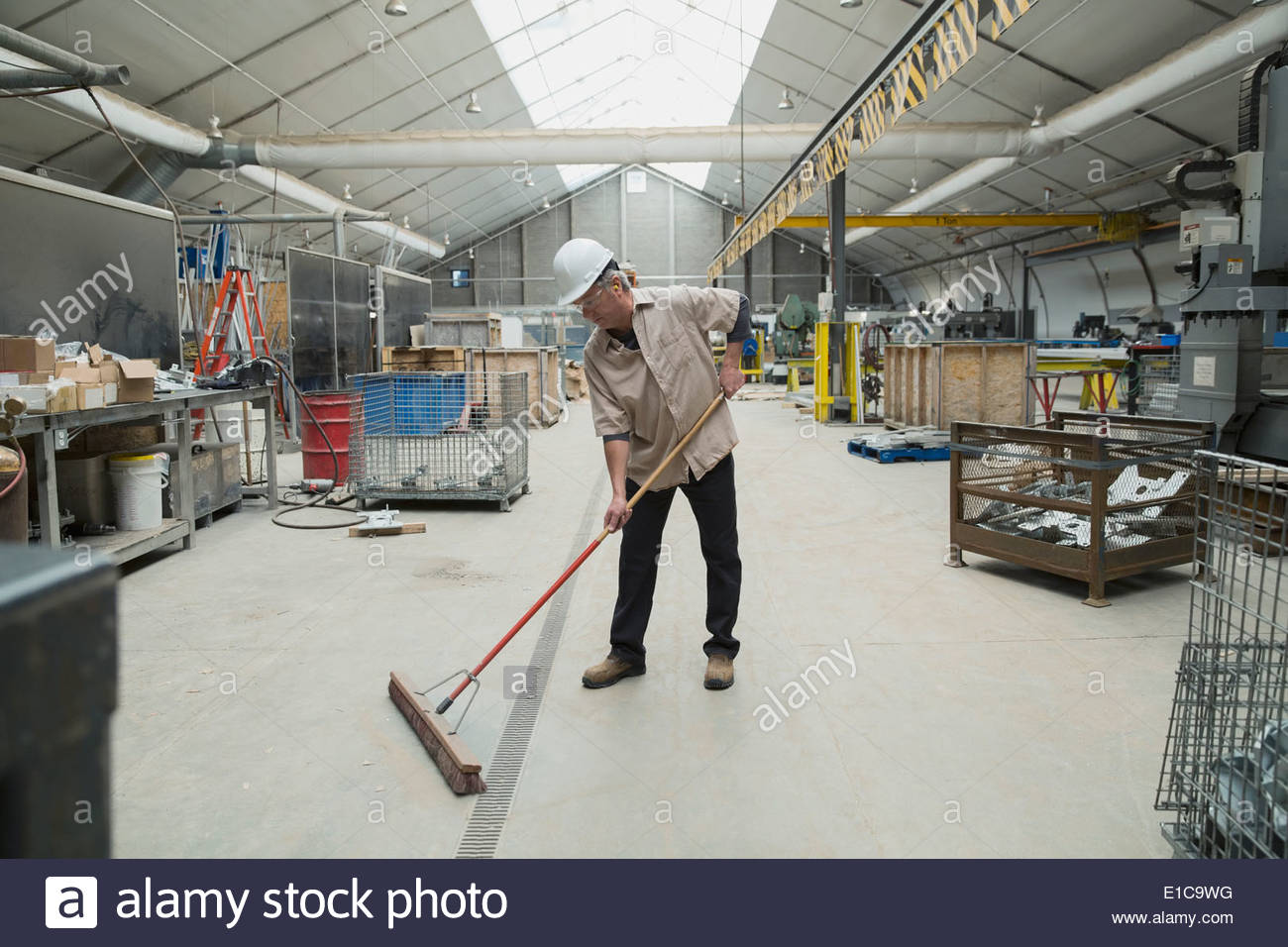 Worker sweeping in manufacturing plant Stock Photo