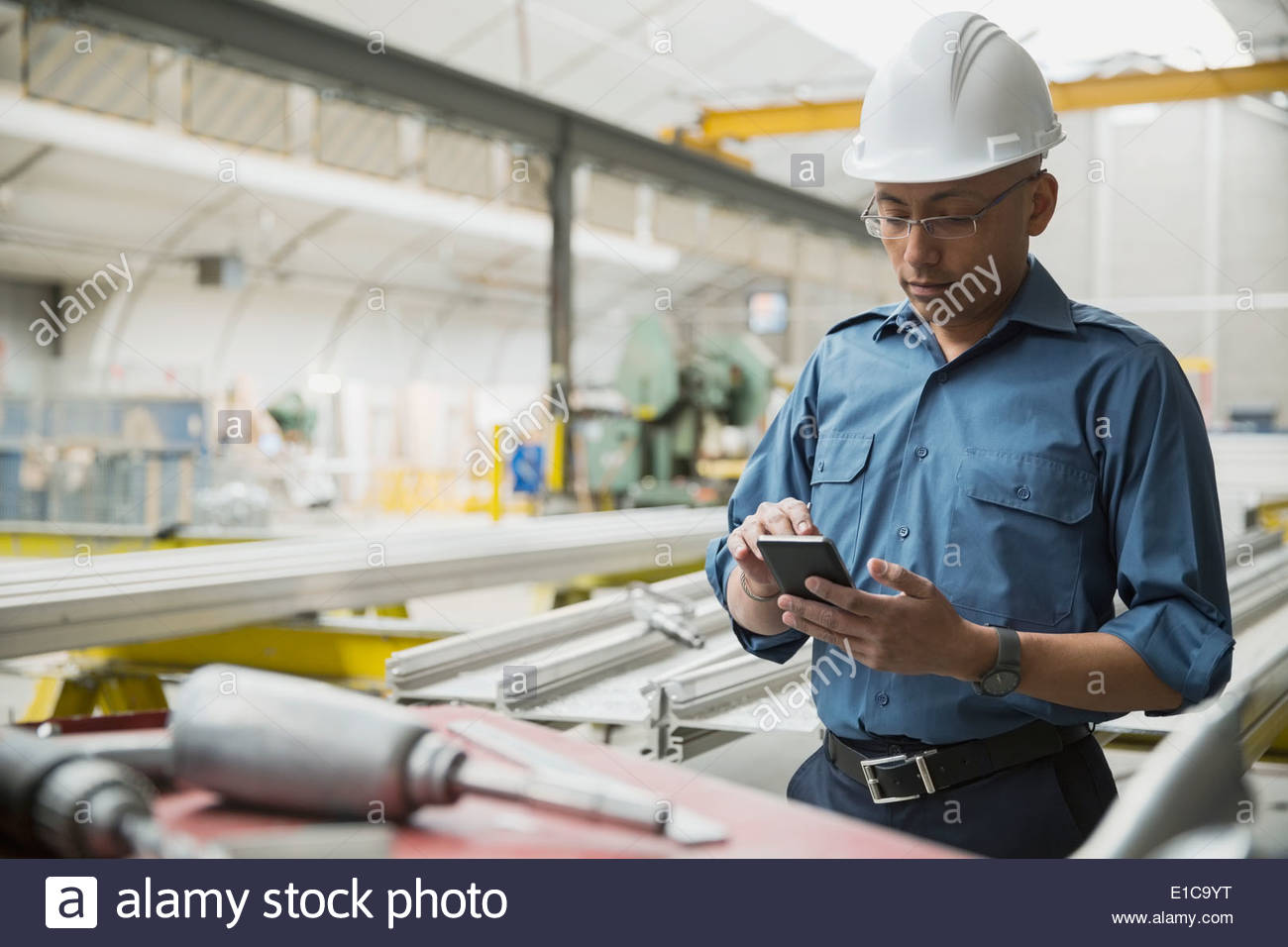 Worker using cell phone in manufacturing plant Stock Photo