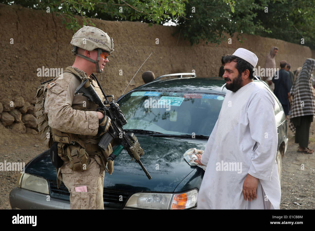 A US Marine with the 1st Battalion, 7th Marine Regiment, speaks to a local villager during a a counter-insurgency mission May 16, 2014 in Larr Village, Helmand province, Afghanistan. Stock Photo