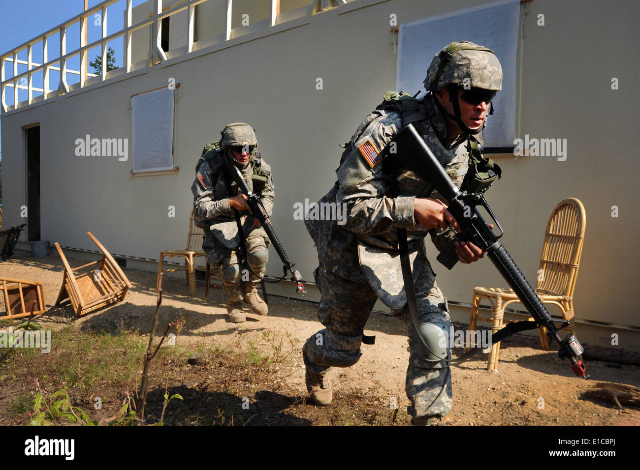 U.S. Soldiers from the Michigan Army National Guard?s 119th Field Artillery Regiment exit a simulated Iraqi building after clea Stock Photo