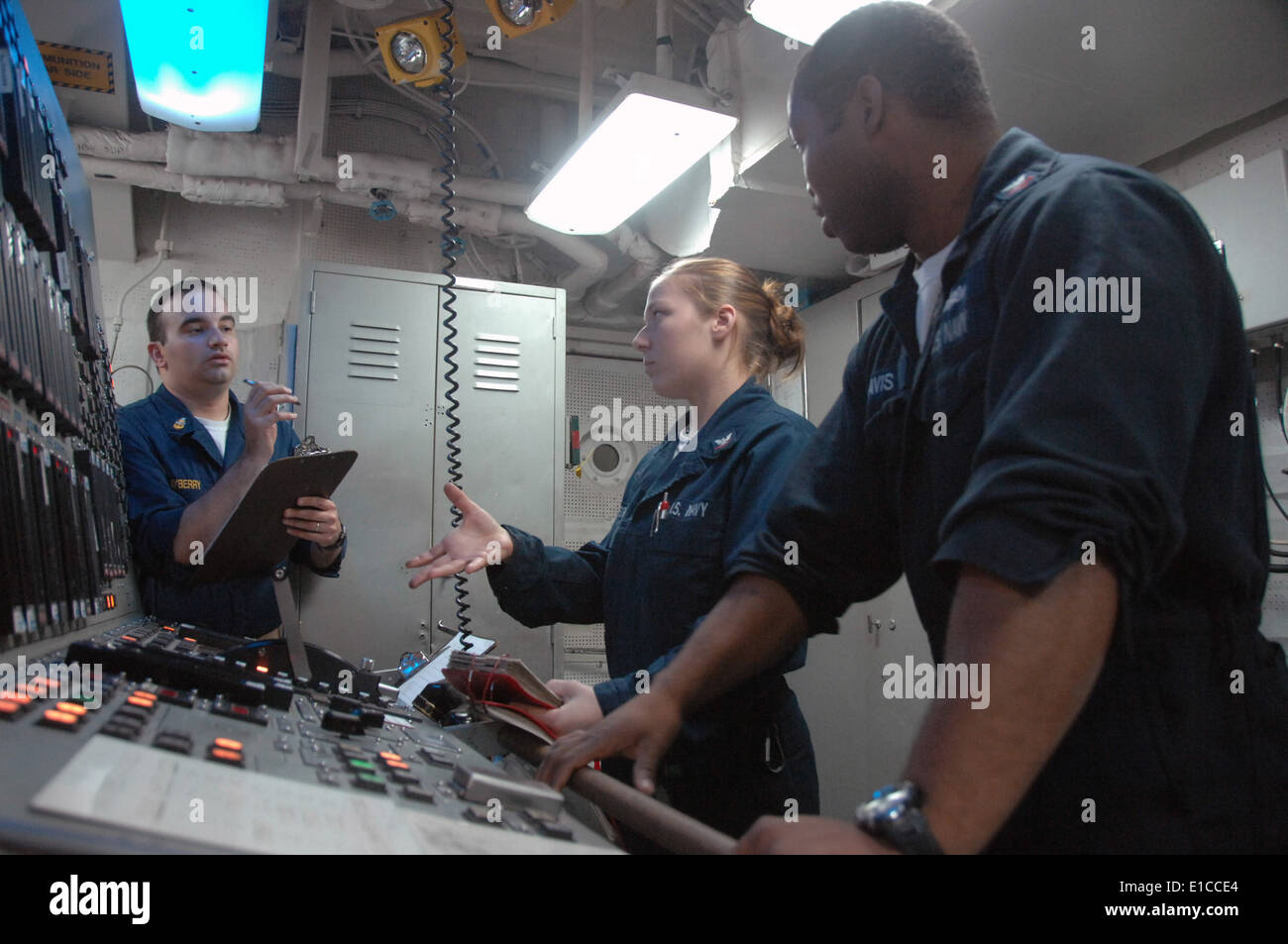 U.S. Sailors aboard USS Oak Hill (LSD 51) discuss procedures in the engineering console control room on board the ship while un Stock Photo