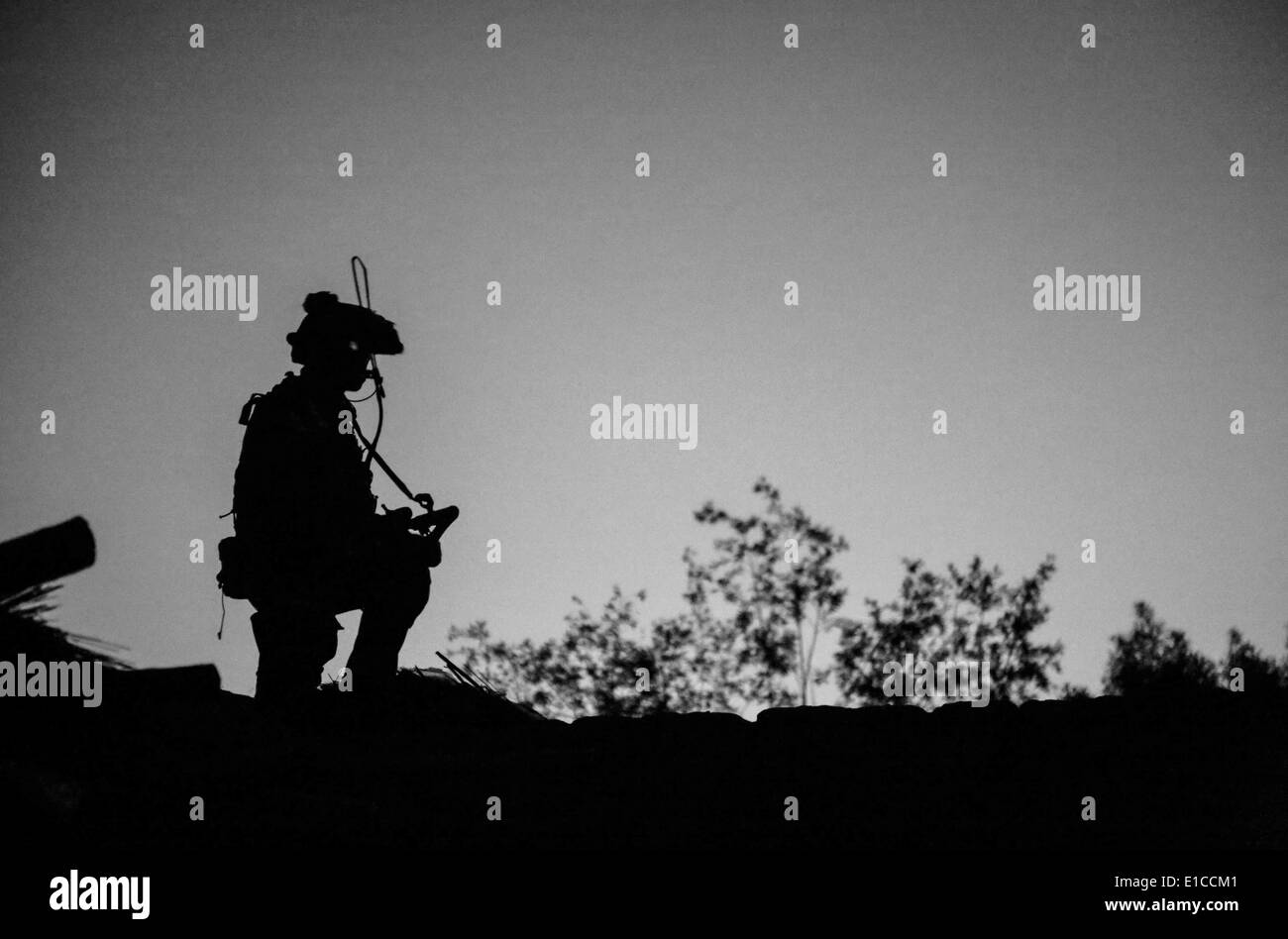 A US Army Special Forces commando uses night vision to scan the horizon from a rooftop during a counter-insurgency operation May 27, 2014 in the Nejrab district, Kapisa province, Afghanistan. Stock Photo