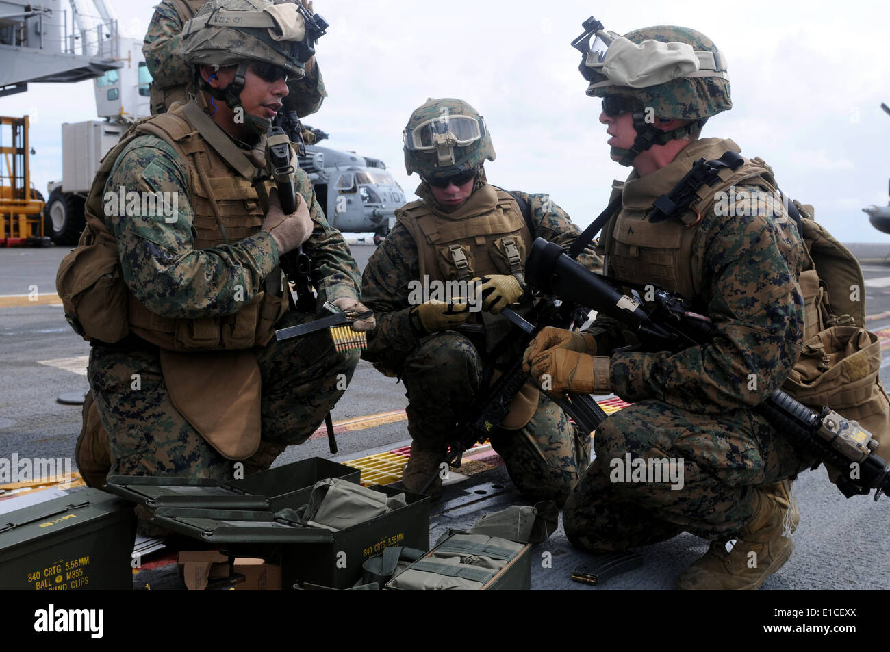 U.S. Marines load ammunition prior to conducting live-fire small arms training on the flight deck of the multipurpose amphibiou Stock Photo