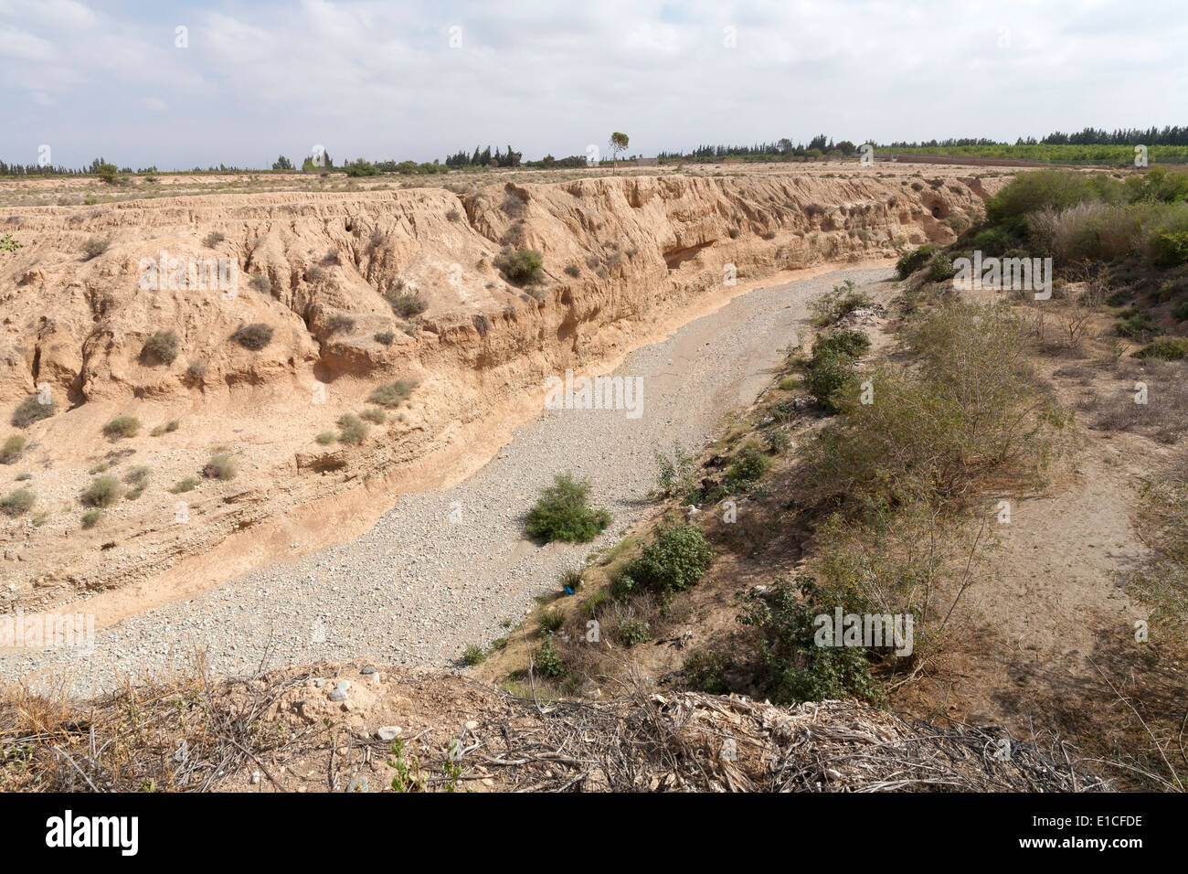 Looking down into a dry wadi with gravel bottom and mud cliffs Stock Photo