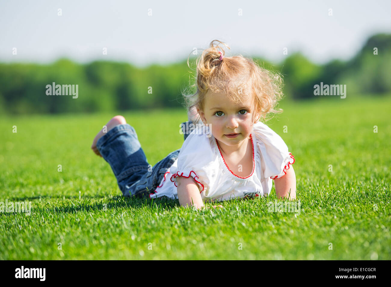 Cute smiling little girl lying on a fresh green grass in a field Stock ...