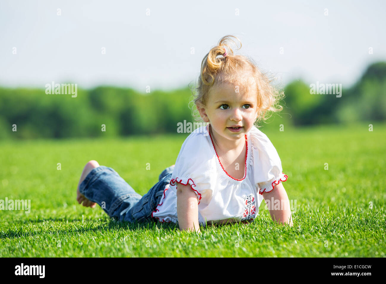Cute smiling little girl lying on a fresh green grass in a field Stock ...