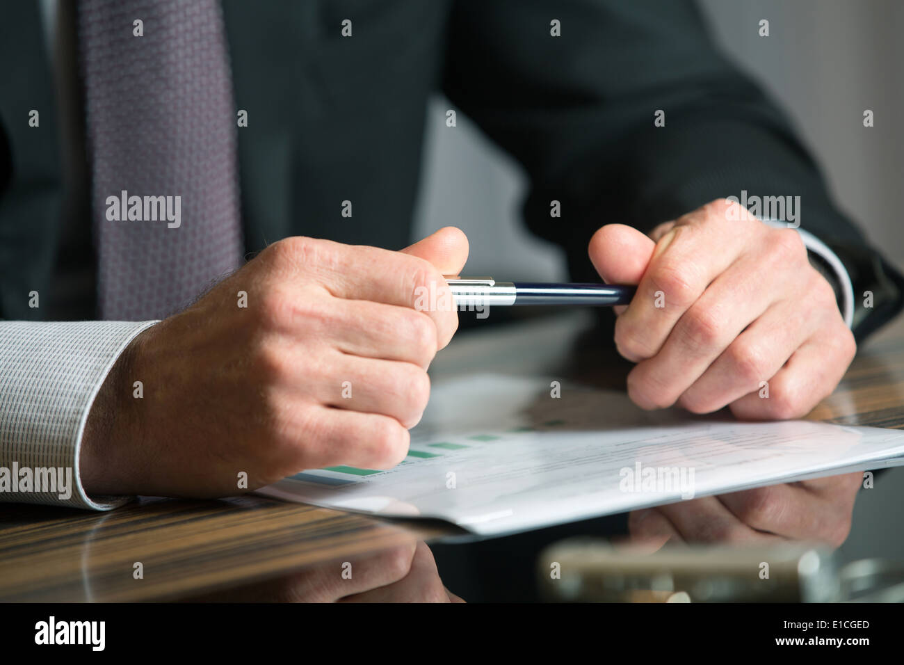 Man's hands holding a black pen in both arms in a thinking gesture during a meeting or negotiation Stock Photo