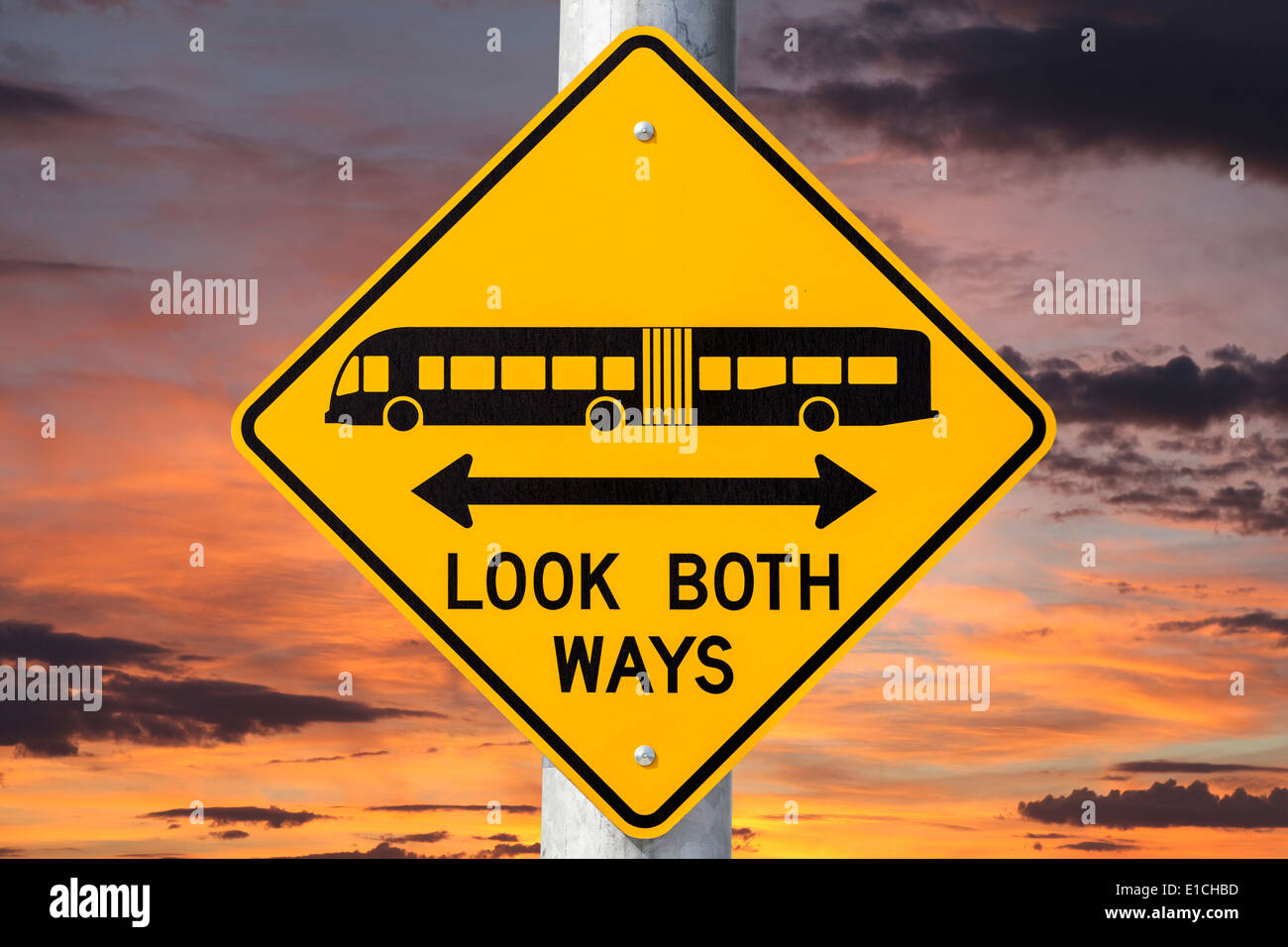 Look both ways bus and tram warning sign with sunset sky. Stock Photo