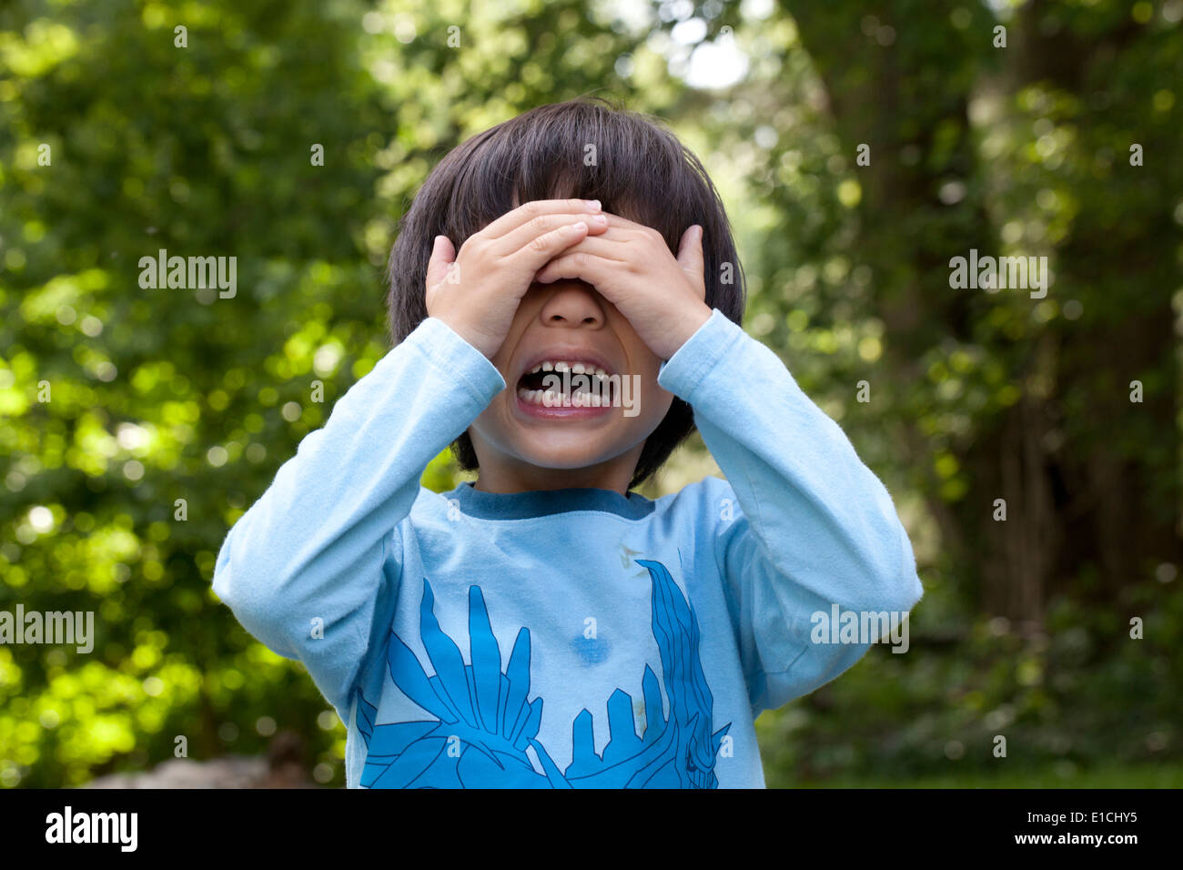 Boy, aged 5, crying with hands over face Stock Photo