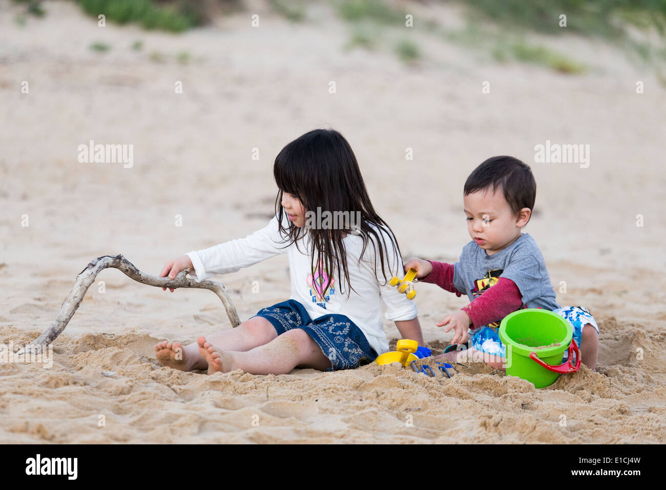 Brother and sister playing in the sand on a beach Stock Photo