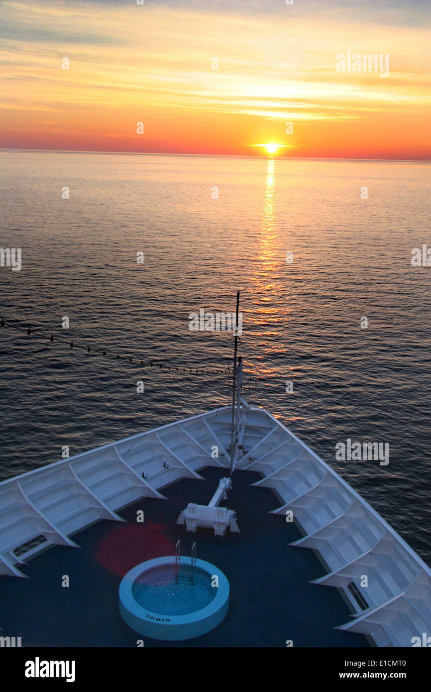 Sunset from the bridge of a cruise ship, the bow is in view & the sun is setting directly ahead with reflections on the ocean. Stock Photo
