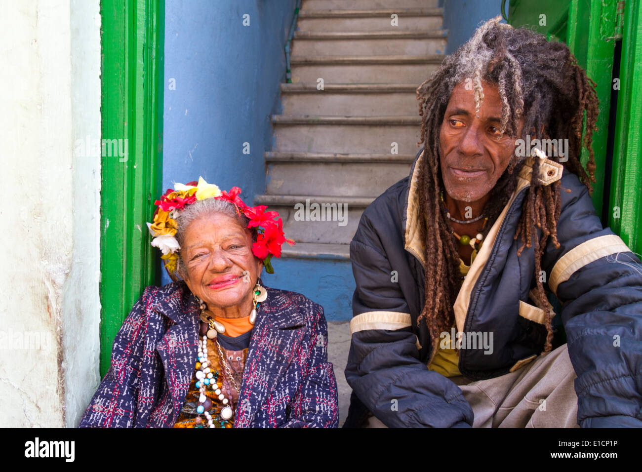 Smiling old lady and Rastafarian man sitting in doorway, in Havana, Cuba Stock Photo
