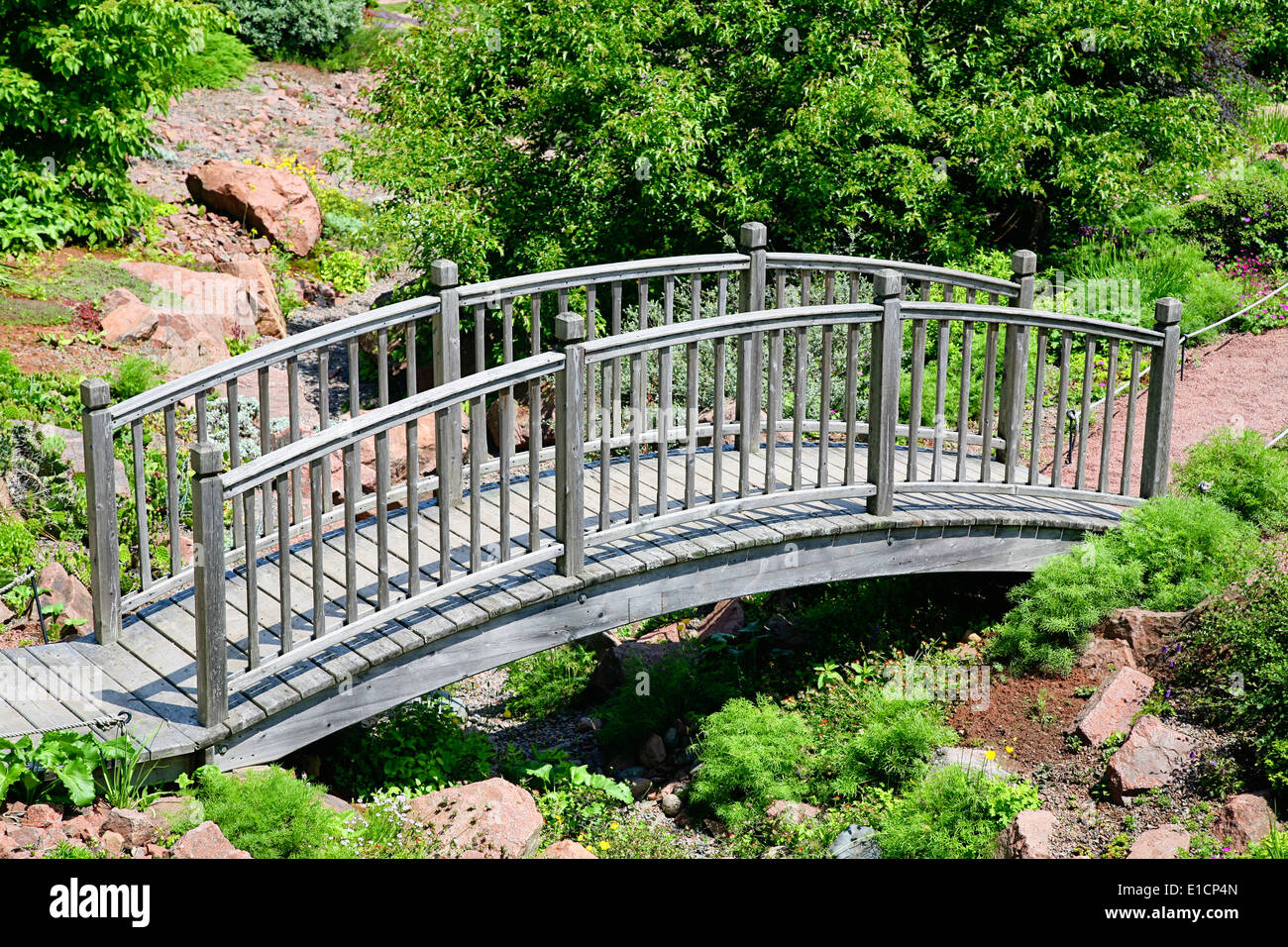 A garden bridge over a gully in an alpine rock garden. Stock Photo