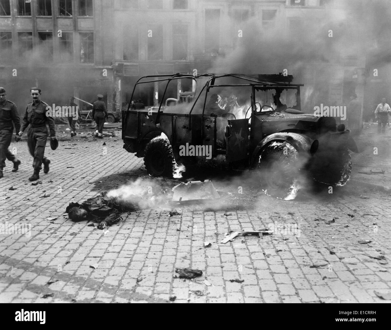 This boy's dead body and burning U.S. Jeep after a V-2 Strike in Antwerp, Belgium, Nov. 27, 1944. Allied soldiers walk nearby, Stock Photo