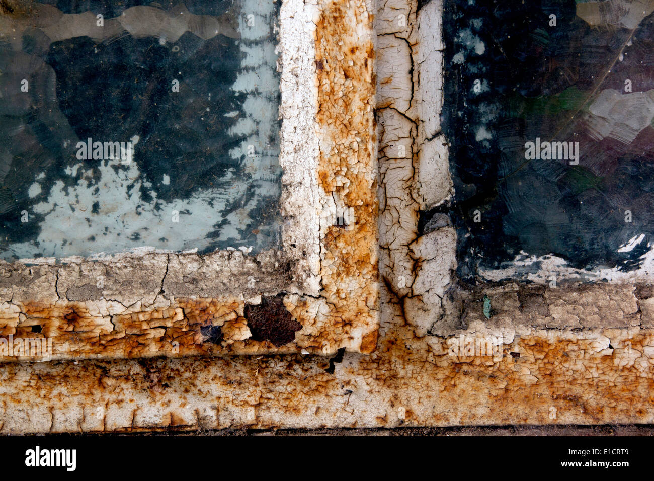 rusty window frame with cracked glass and flaking putty Stock Photo