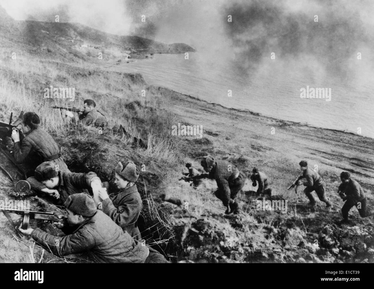 World War 2, Soviet female medic in battle. Soviet soldiers fighting up a hill from a beach; in foreground a woman medic Stock Photo