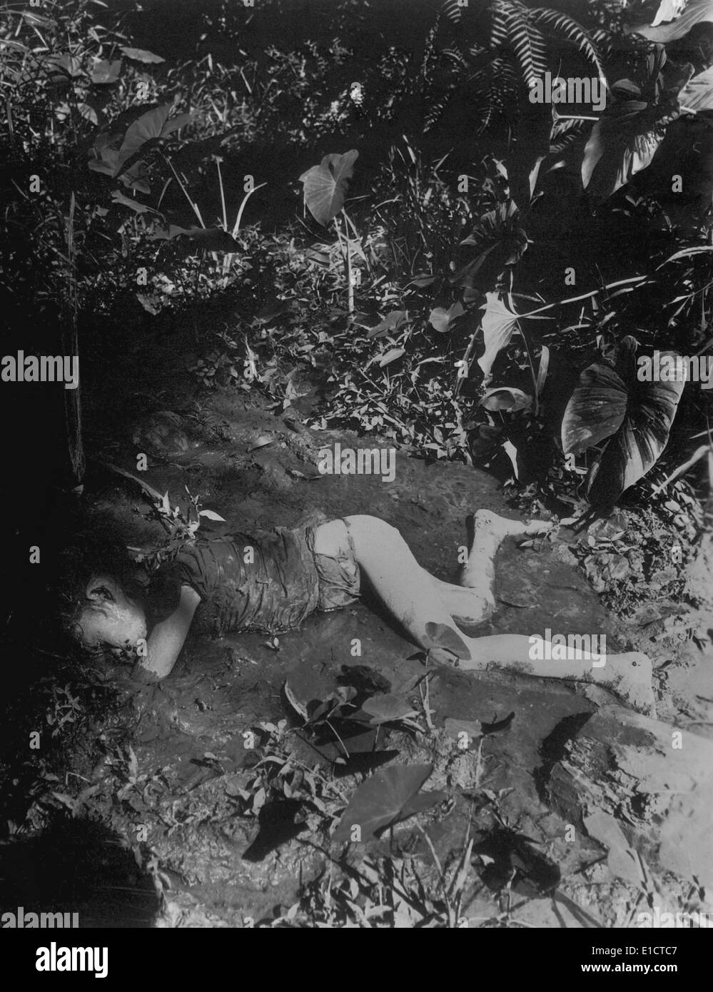 Dead Filippino child laying in mud of creek killed by Japanese on April 9, 1945 at Bingas, Luzon. Philippine Islands. World War Stock Photo