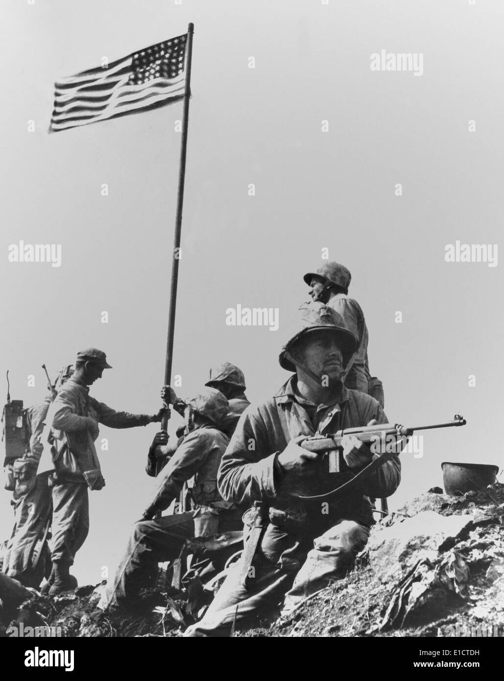 The first flag raising on Iwo Jima's Mount Suribachi, Feb. 23, 1945. A Marine guards the Fifth Division Marines of the 28th Stock Photo
