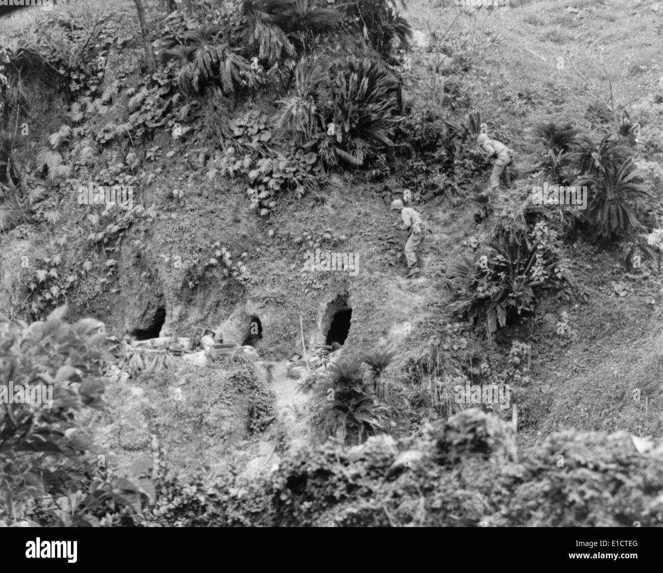 Two U.S. soldiers to throw grenades into Japanese held caves on Okinawa Island, May 16, 1945. Soldiers are with the 27th Stock Photo