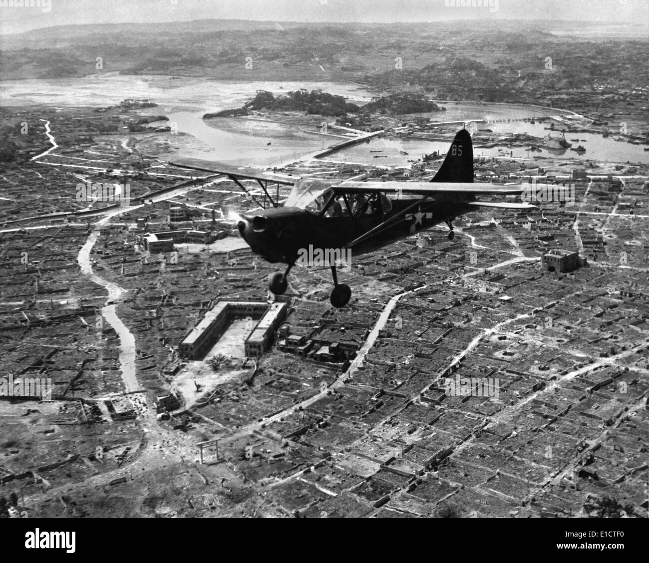 U.S. Marine observation plane flies low over Naha, capital of Okinawa, May 1945. The small plane drew small arms and Stock Photo