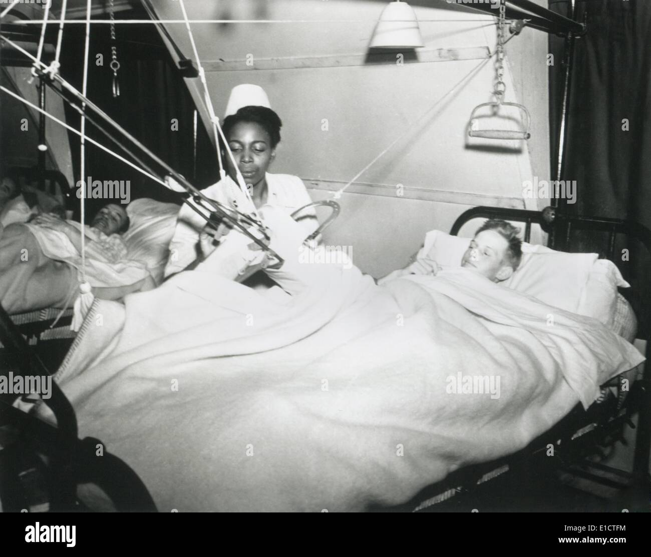 African America U.S. Army Nurse treats a German POW at a prisoner-of-war hospital in England. Oct. 7, 1944. Official racial Stock Photo