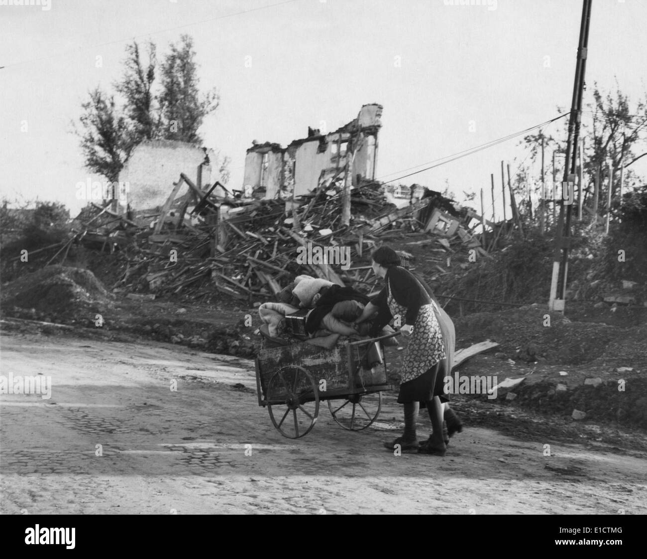 Two German women pushing their belongs in a cart past demolished buildings, Aachen, Germany. The battle of Aachen took place Stock Photo