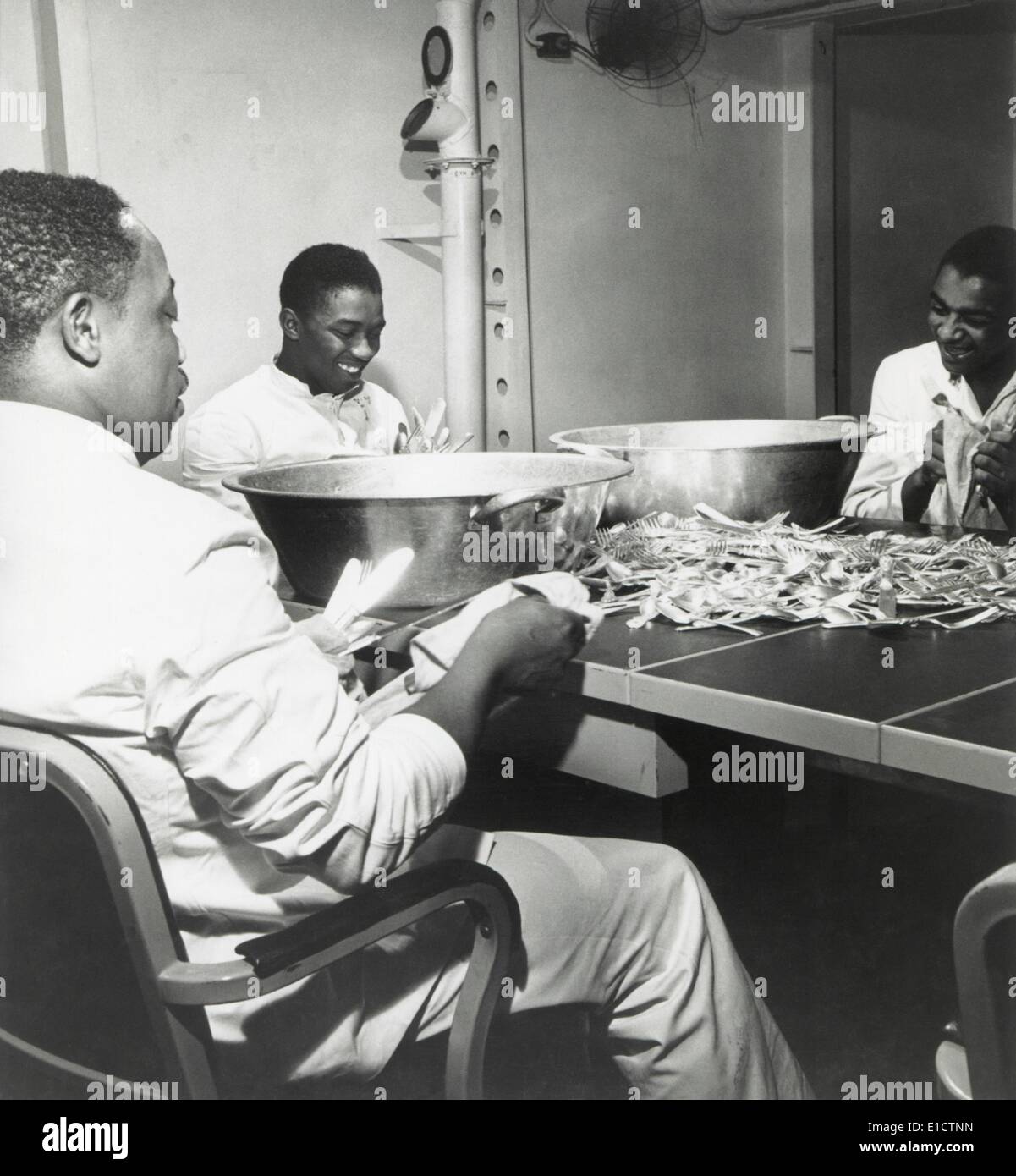 African American steward mates dry silverware in the wardroom of the U.S.S. Ticonderoga. The segregated Navy filled mess Stock Photo