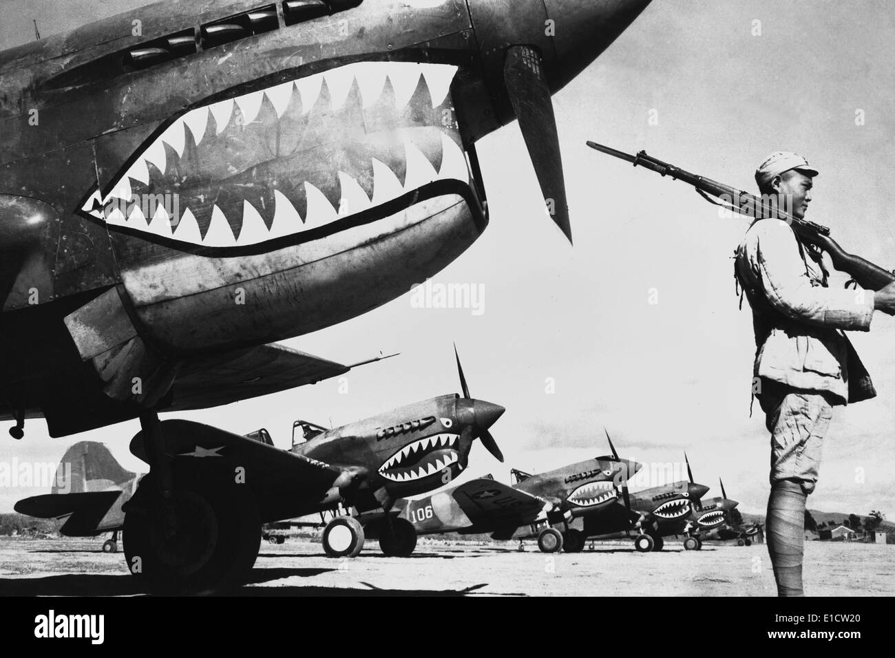 Chinese soldier guards a line of American P-40 fighter planes, ca. 1942. The shark-face fighters of the 'Flying Tigers' had a Stock Photo