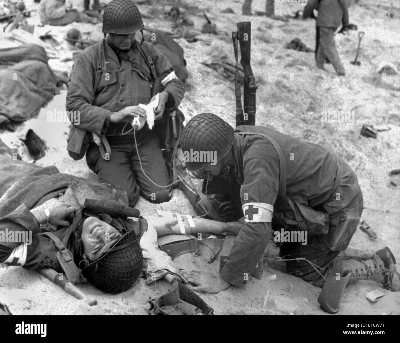 Medics treat a wounded U.S. soldier on D-Day. During the Normandy landings in Nazi occupied France, June 6, 1944, World War 2. Stock Photo