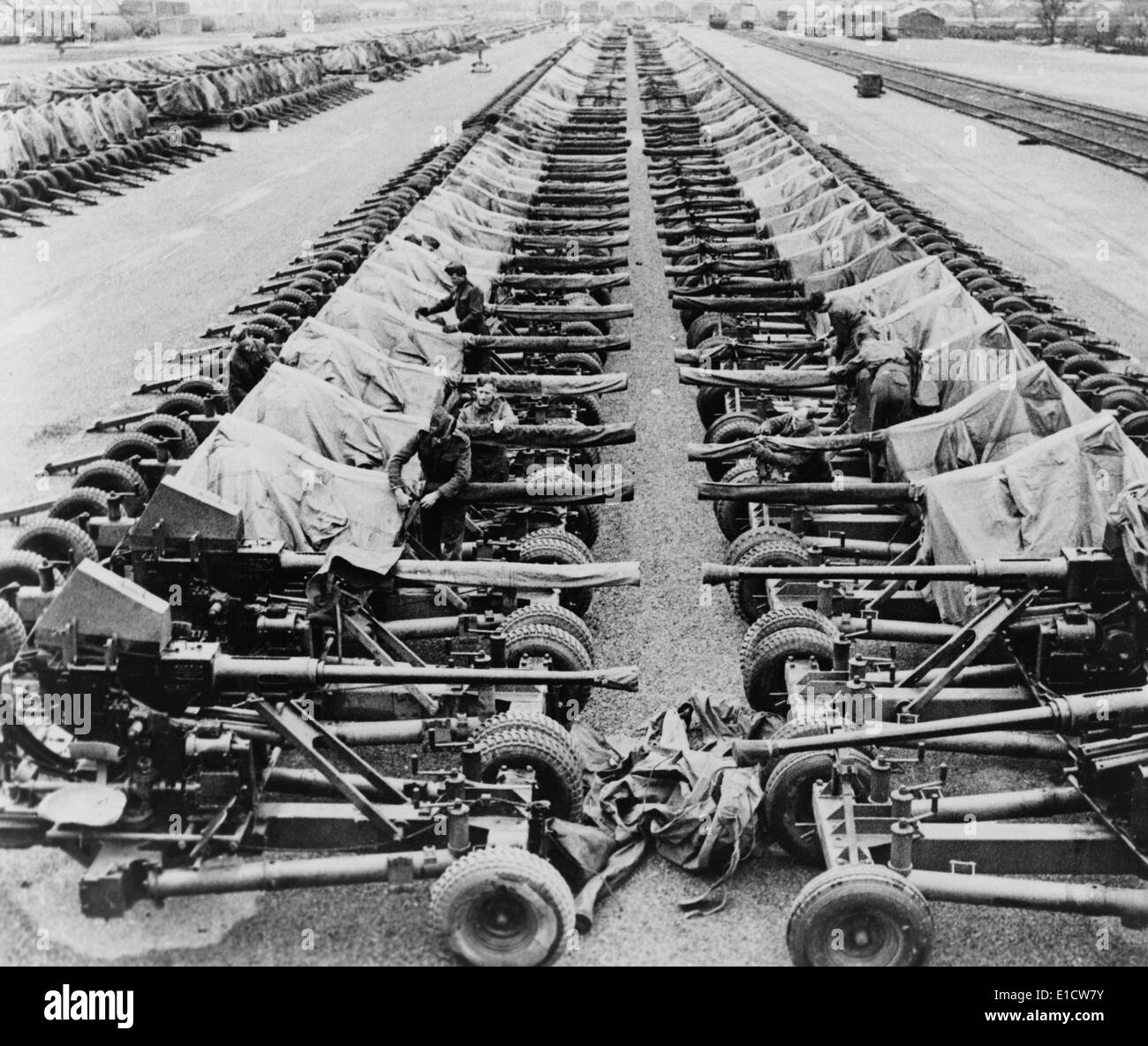 Rows of 40mm Bofors light anti-aircraft guns beside railroad tracks in England. There was a massive build up of soldiers and Stock Photo