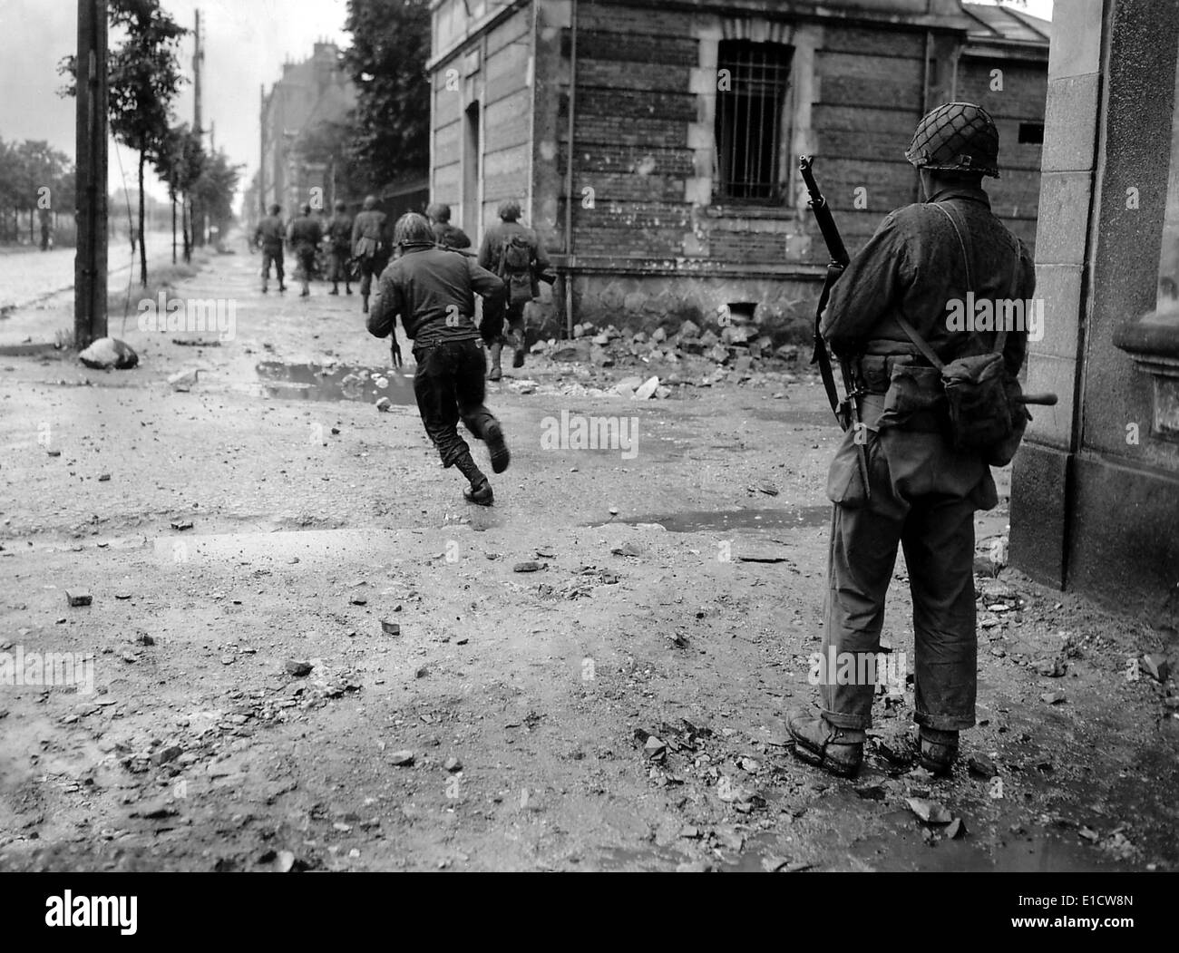 U.S. soldiers moving through the streets of Cherbourg. One by one they dash across a street to evade German sniper fire. June Stock Photo