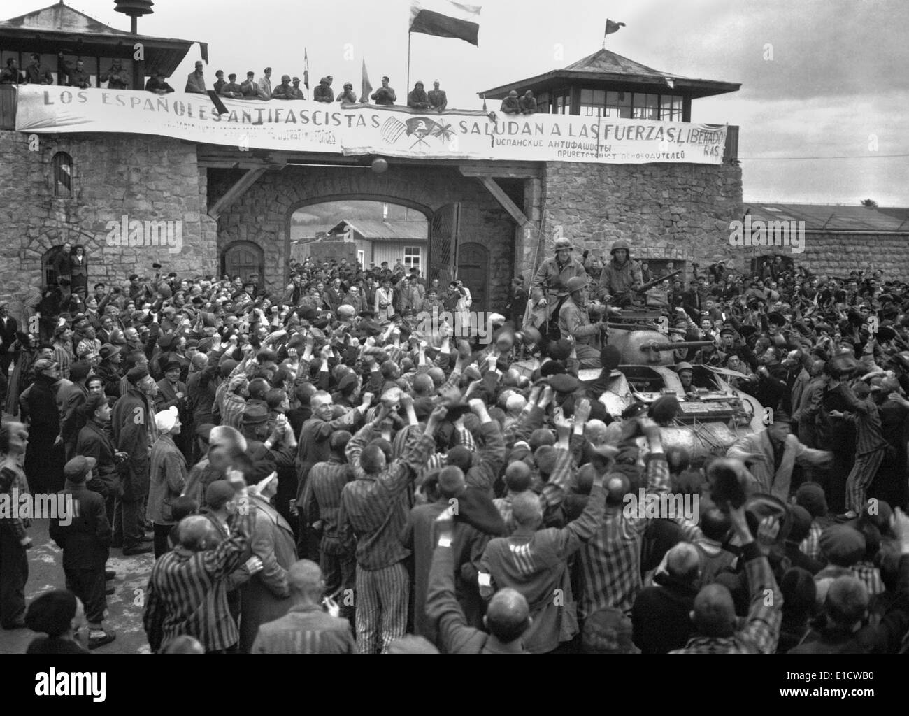 Liberated prisoners in the Mauthausen concentration camp cheer U.S. soldiers. The banner across the wall was made by Spanish Stock Photo