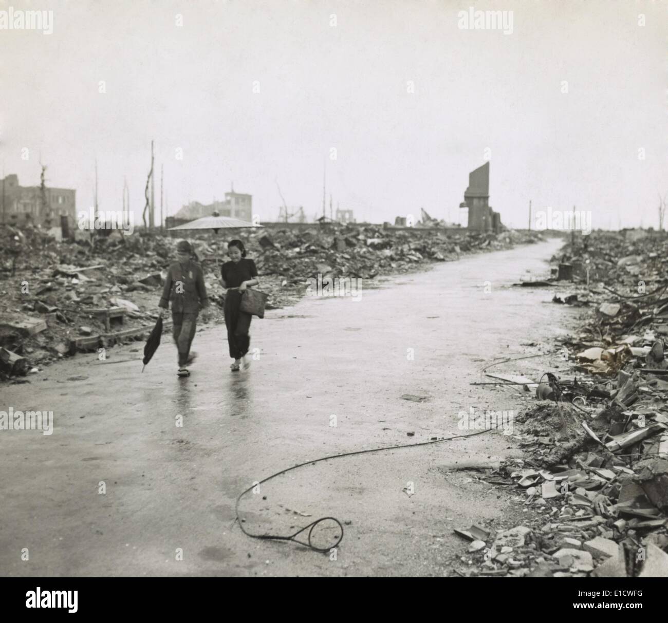 Two Japanese civilians walk through cleared path in Hiroshima's ruins ...