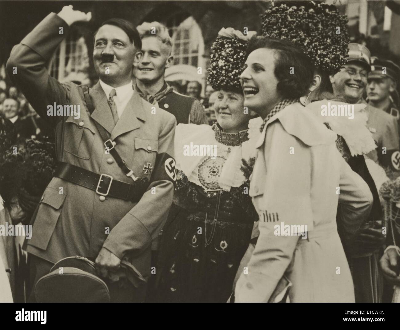 Adolf Hitler and filmmaker, Leni Riefenstahl, with joyous smiles. They are in a group with woman wearing traditional German Stock Photo