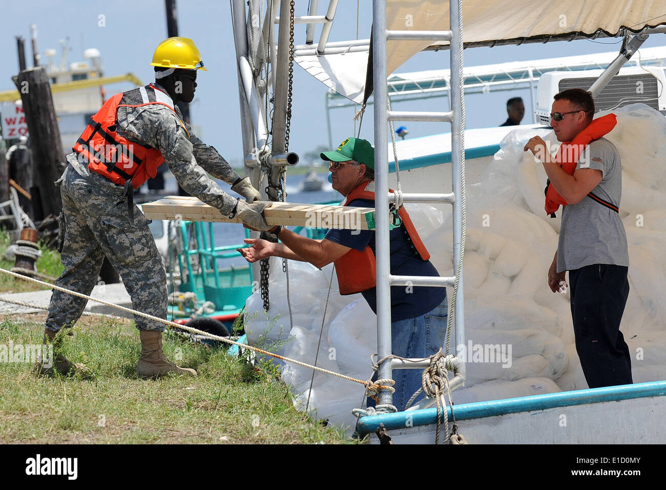 U.S. Soldiers from the Louisiana Army National Guard load oil spill boom materials onto local fishing boats at the Breton Sound Stock Photo