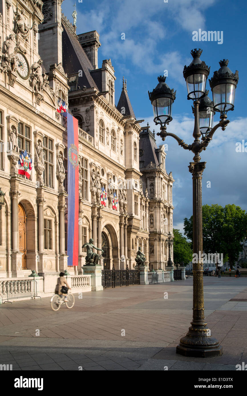 Bicycle riding past Hotel de Ville near sunset, Paris France Stock Photo