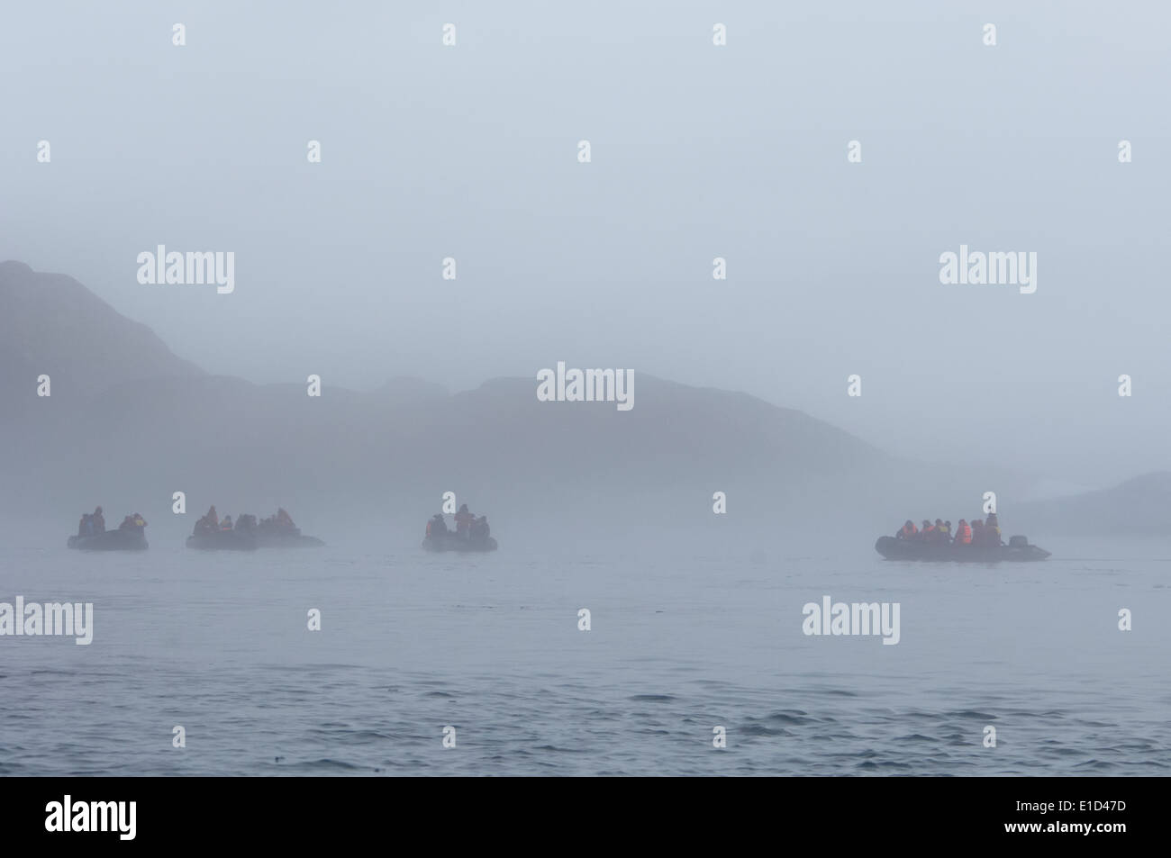 Zodiac boats with people, traveling along the cliffs in Nunavut, Canada