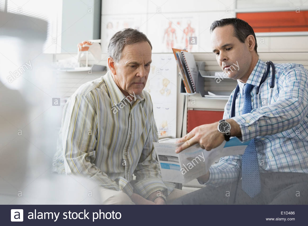 Doctor showing senior patient brochure in office Stock Photo