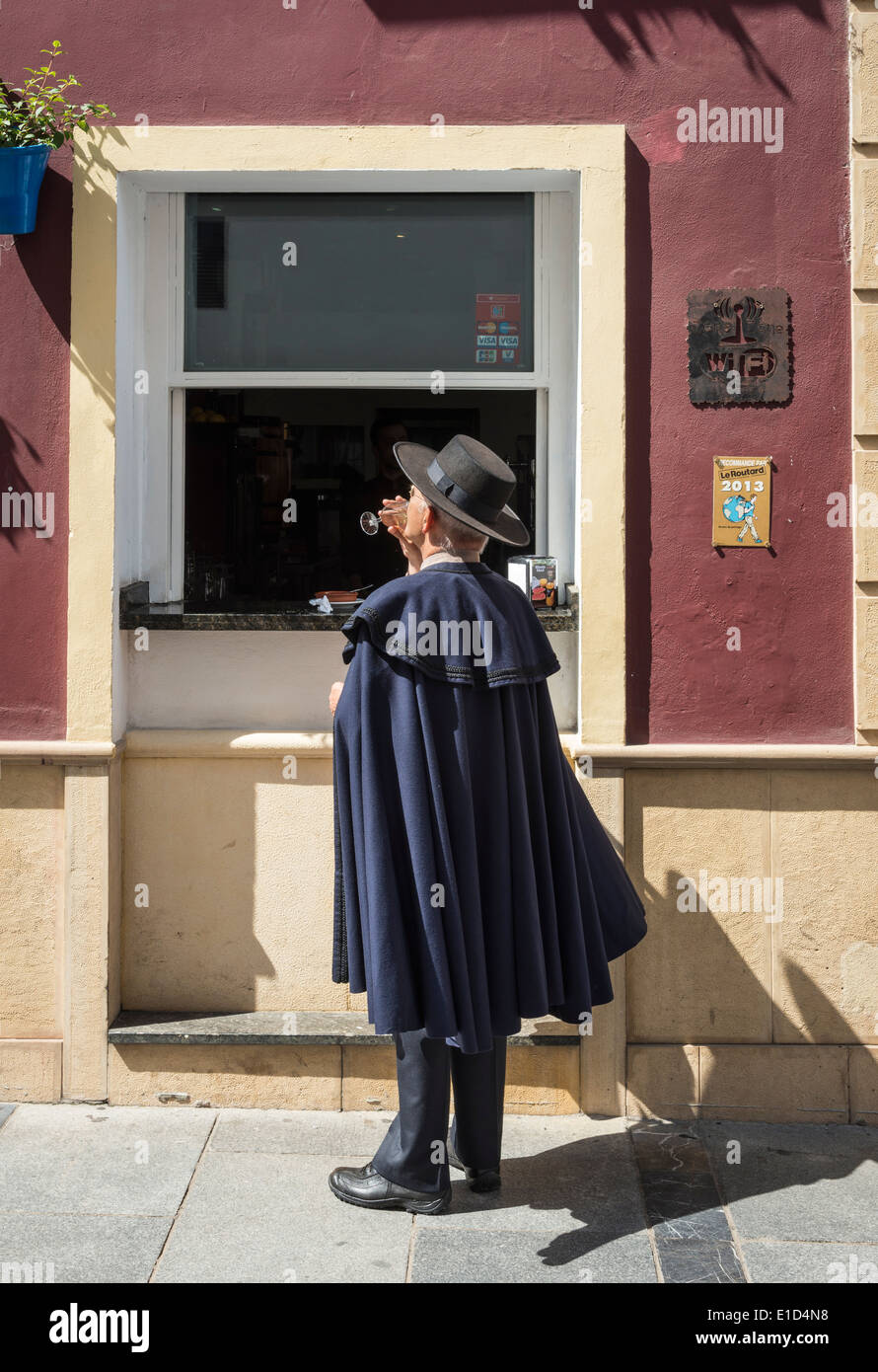 A man in a traditional Andalucian hat and cloak stops for a drink at a bar near the Plaza del Potro Cordoba, Andalucia, Spain. Stock Photo