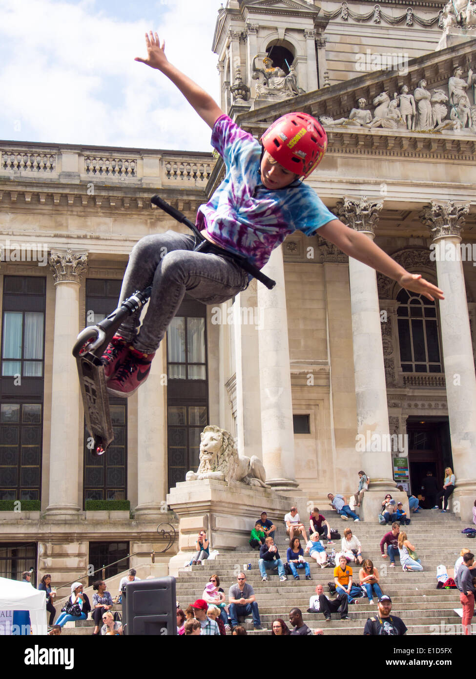 A young ten year old  scooter rider performs an aerial stunt in front of the Portsmouth Guildhall during the Portsmouth street games 2014 Stock Photo