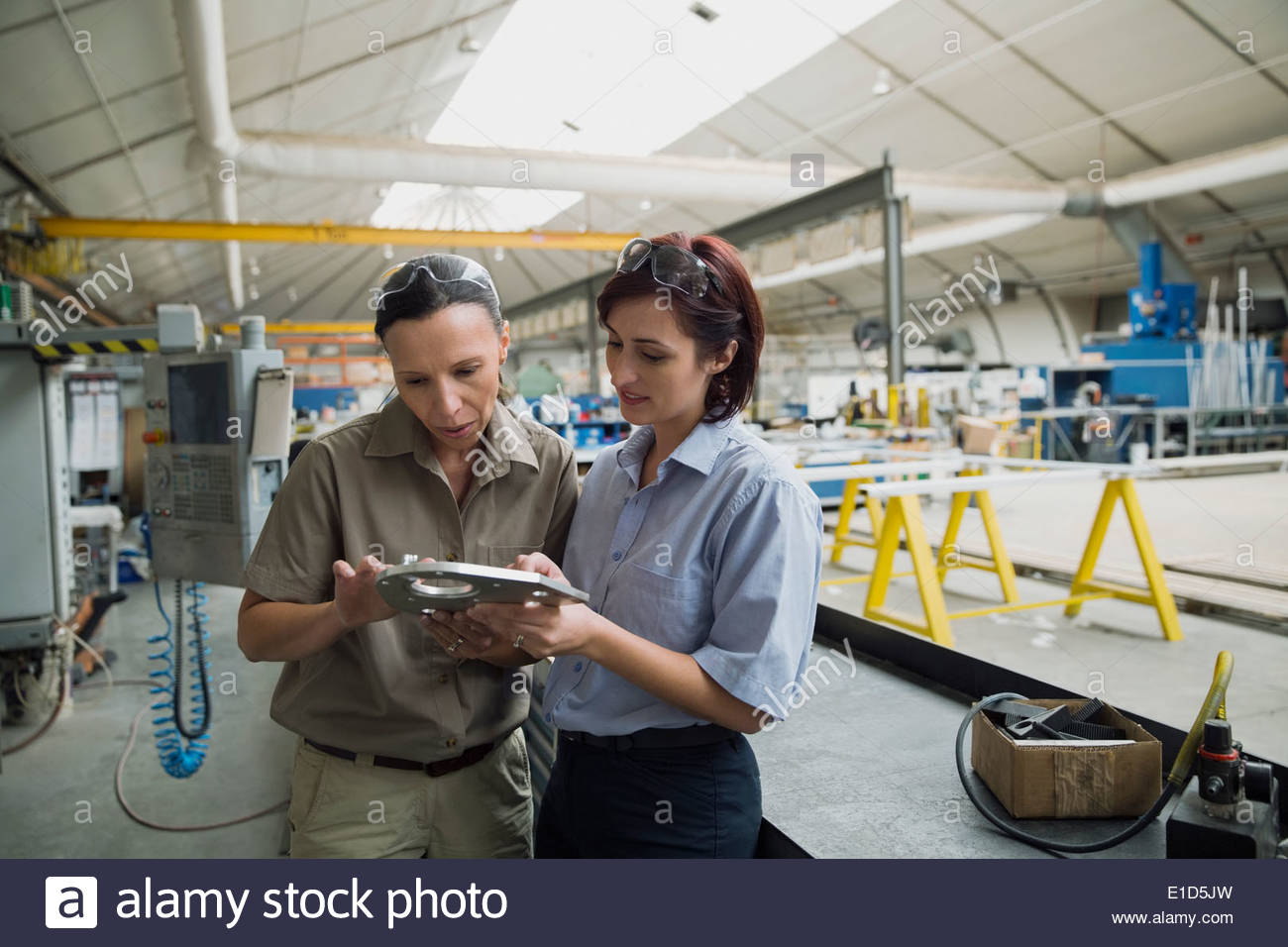 Workers examining metal part in manufacturing plant Stock Photo