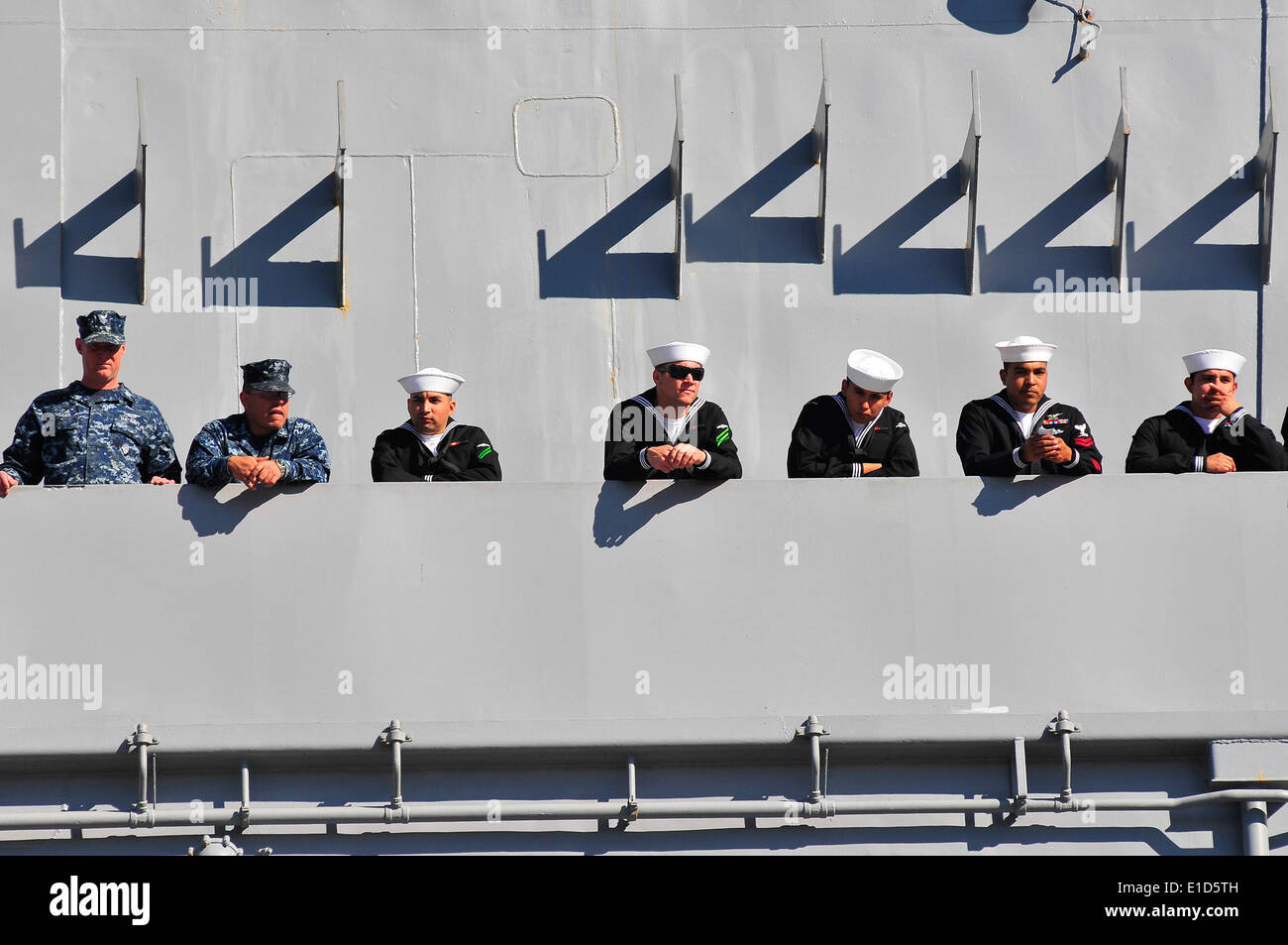 U.S. Sailors assigned to the aircraft carrier USS Carl Vinson (CVN 70) watch family members on the pier from the ships? catwalk Stock Photo