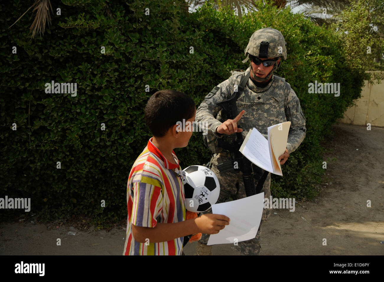 U.S. Army Spc. Nick Weber, from the 303rd Psychological Operations Company, hands out an activity sheet to an Iraqi boy during Stock Photo