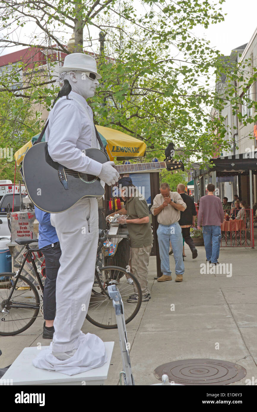 Asheville, North Carolina, USA - April 26, 2013: 'Man In White' a living statue poses and plays guitar for tips on the street Stock Photo