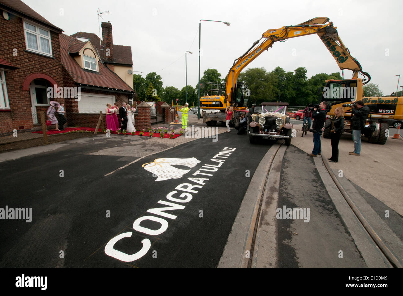 Beeston, Nottingham, UK. 31st May, 2014. Bride Hannah Kirk of Beeston Nottingham, UK, had a suprise , when workmen building the net tramline downed tools to give her a special wedding morning send off. Two diggers formed a processional arch, road sign painters wrote 'congratulations' on the road outside her parents house, and a engineer wearing a hard hat played his flute as the bridal party emerged. Credit:  Jon Legge/Alamy Live News Stock Photo