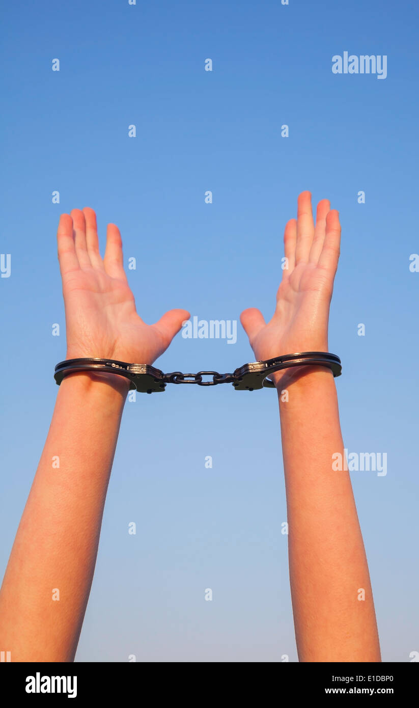 Handcuffed woman hands against blue sky Stock Photo