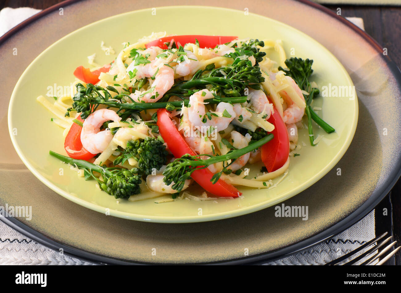 Linguine with shrimp, broccolini and red peppers on a wooden surface Stock Photo