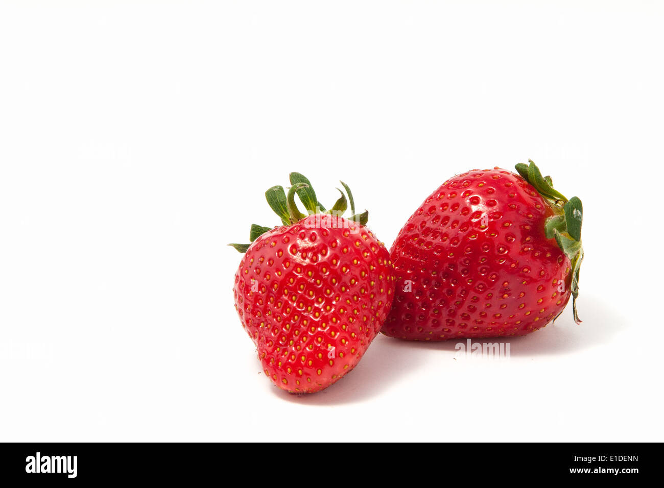 Two strawberries with leaf on white background Stock Photo - Alamy