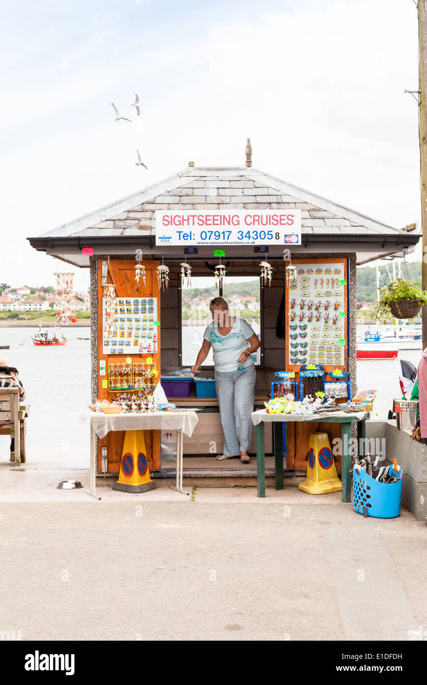 Small seaside novelty stall at Conway quayside North Wales filled with various novelty gifts, Caucasian woman inside looking out Stock Photo